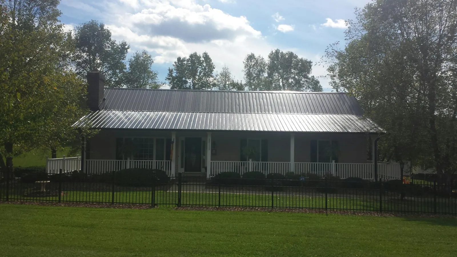 Gray metal roof on a brick ranch with a full width front porch — Gutter Guard Installation work by our crew in Deforest