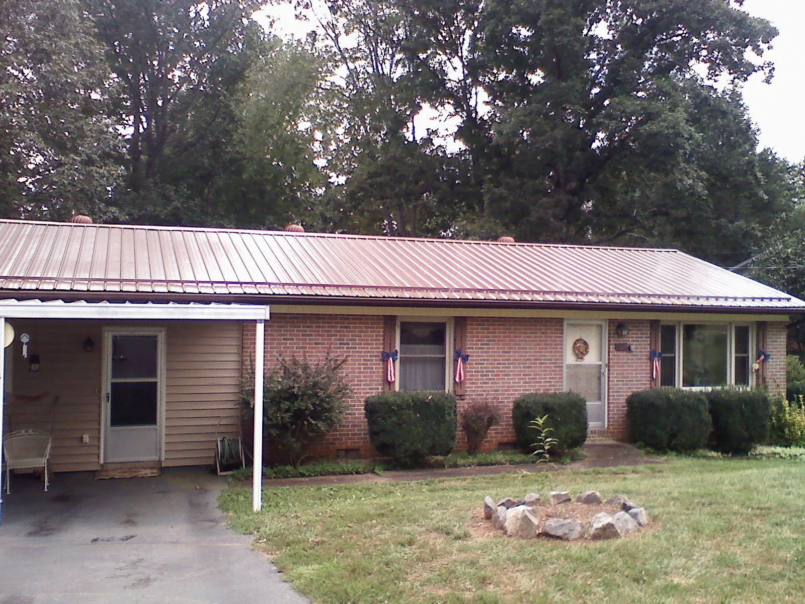 Bronze metal roof and carport on a brick ranch home — Roof Repair work by our crew in Deforest