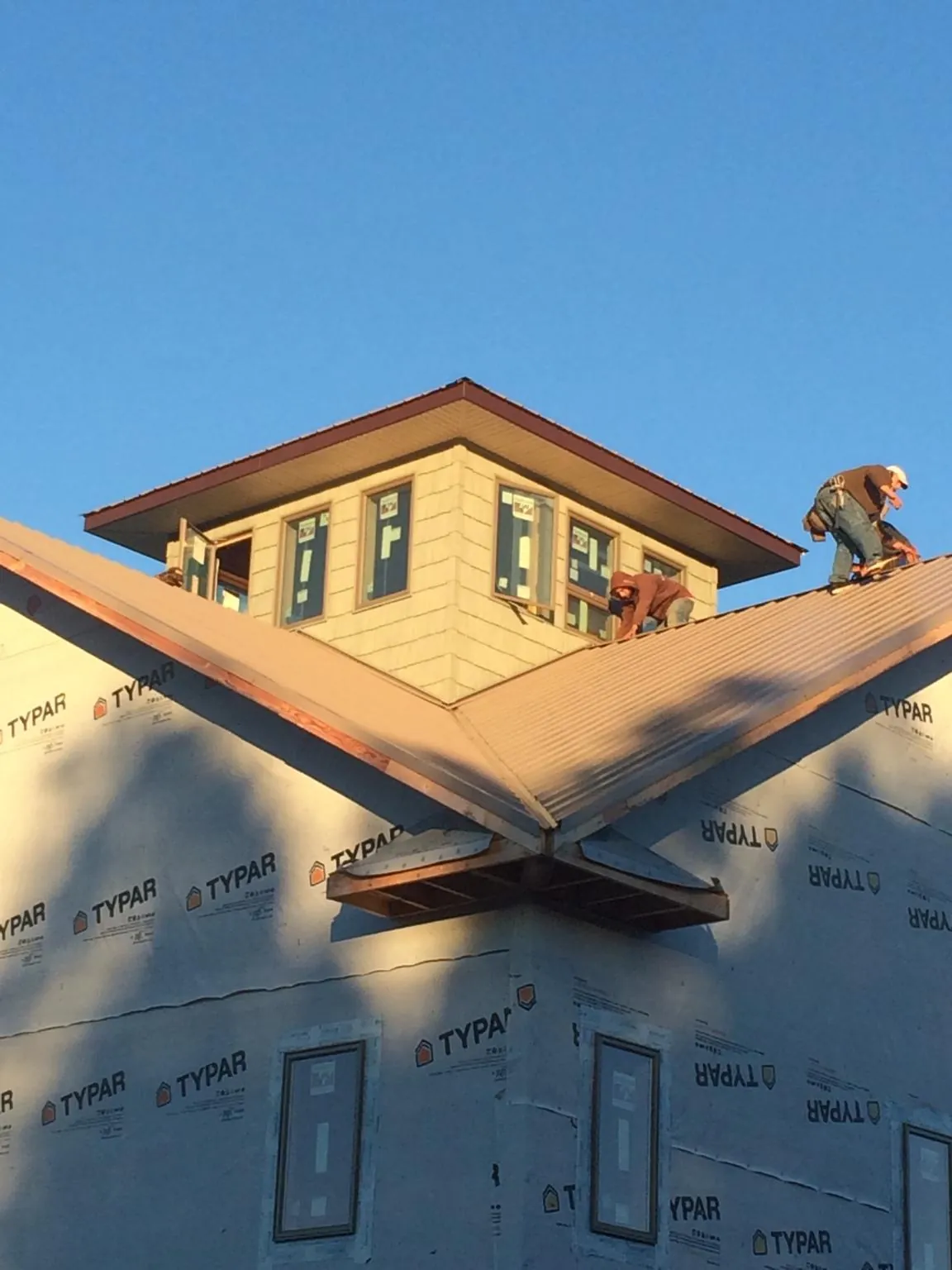 Roofers working around a rooftop cupola on a new metal roof at sunset — Roof Waterproofing in Deforest by Roofing Brothers
